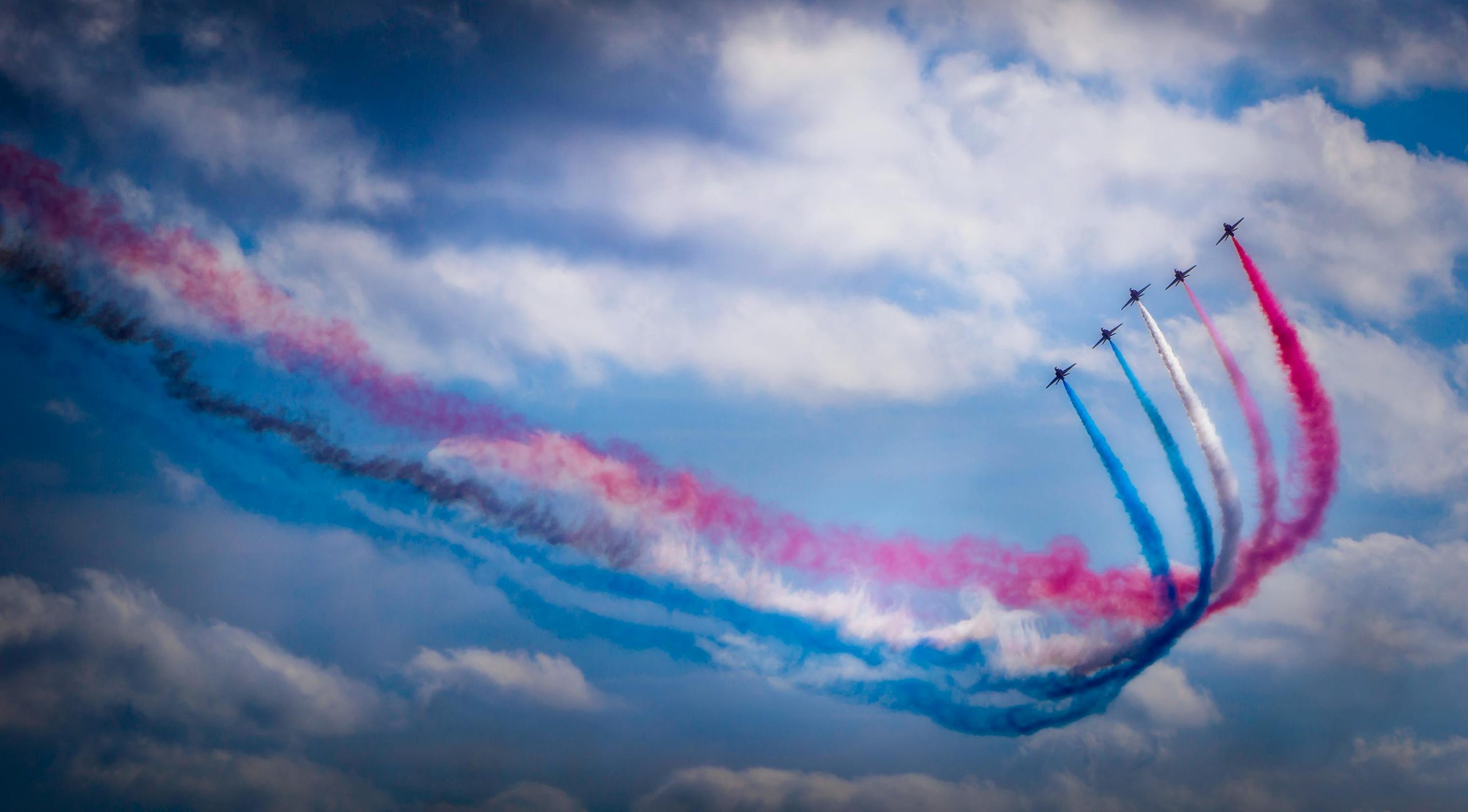 A stunning aerobatic display featuring colorful smoke trails against a clear blue sky.